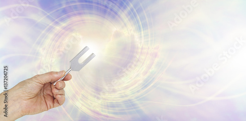 If you could see the sound waves make by an Angel Tuning Fork - female hand holding a short aluminum tuning fork on a graphic depiction of angelic sound waves background