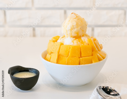 Bingsu mango served with sweetened condensed milk on table- Korea dessert
