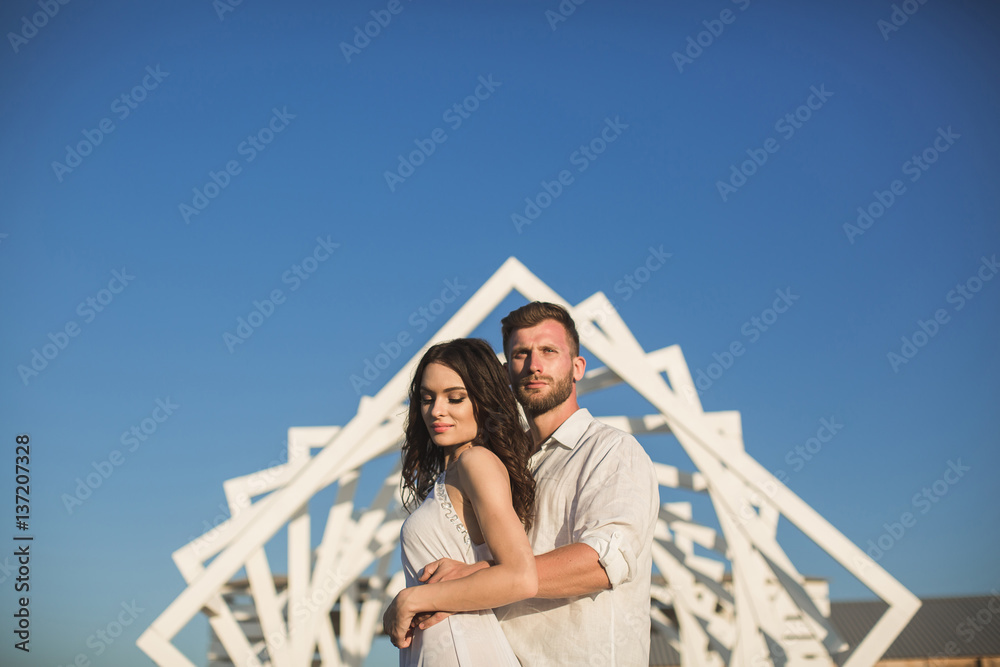 Man and woman posing. Geometric wooden structures. The bride and groom.