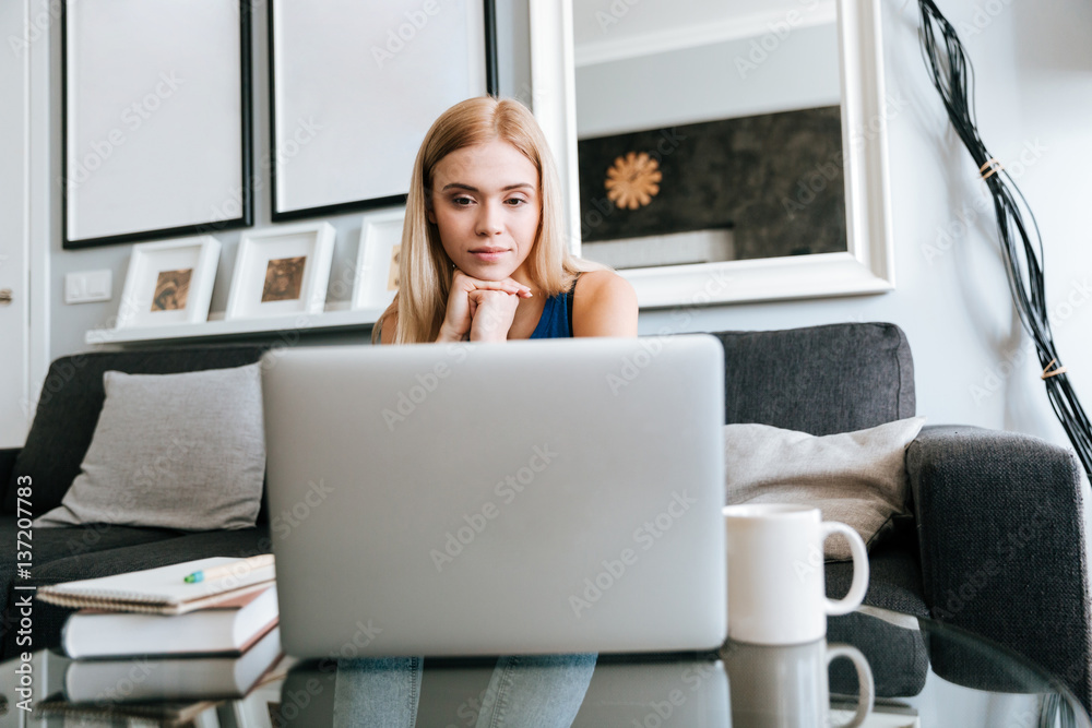 Pensive woman thinking and using laptop at home Pensive woman thinking and using laptop at home