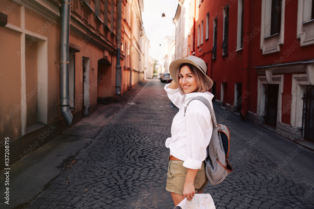 Travel guide. Young female traveler with backpack and with map on the street.