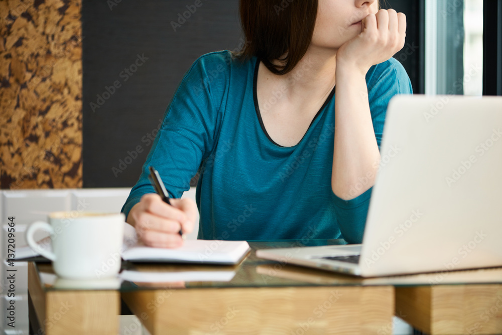 Woman thinking near the window and making notes Woman thinking near the window and making notes