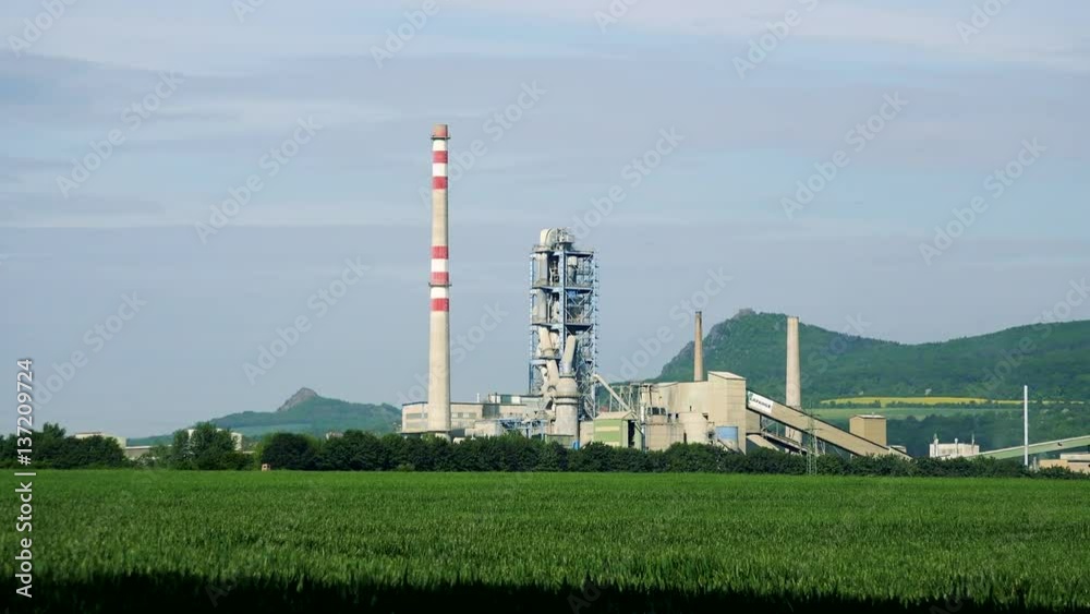 A factory from a distance - a meadow in the foreground, mountains and the sky in the background A factory from a distance - a meadow in the foreground, mountains and the sky in the background