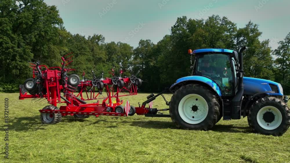 A farmer sitting in a tractor is pushing a button and the rotary rakes machinery is slowly opening and then he will be able to start working.
A farmer sitting in a tractor is pushing a button and the rotary rakes machinery is slowly opening and then he will be able to start working.