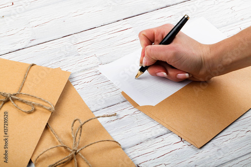 Woman writes something on white paper in yellow envelope photo