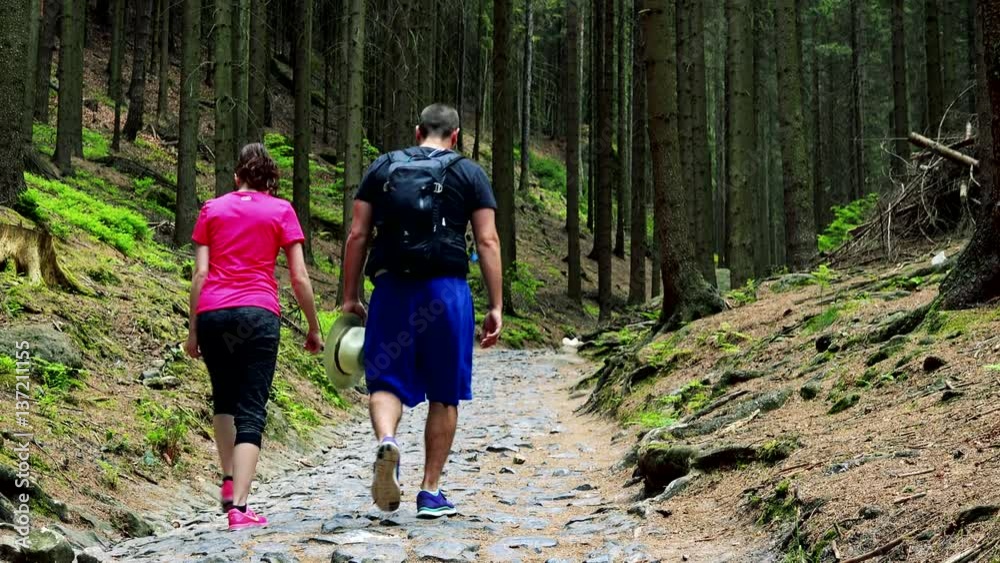 A couple walks down a flagged pathway into a forest A couple walks down a flagged pathway into a forest