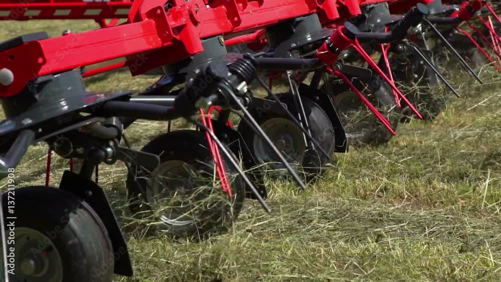 We can see fast movements of rotary rakes. The tractor is pulling a ...