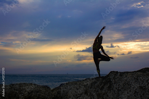 Silhouette of person doing yoga. Silhouette of woman standing in yoga pose on the background of the sea. 