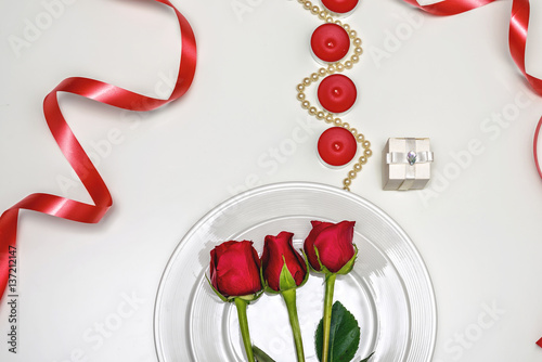 Red Roses on a white plate, candles and giftbox. Romantic composition for Val...
