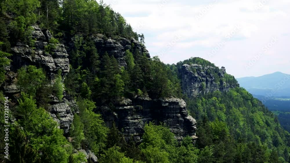 Rocks covered with trees and a forest under them Rocks covered with trees and a forest under them