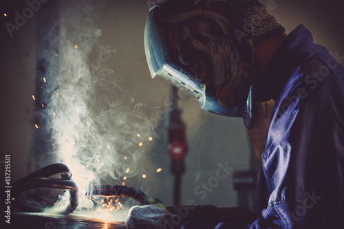Industrial background of a man welding steel pipe generating sparks and gas