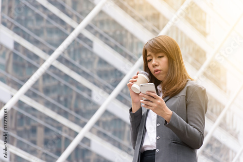 Business woman using a communication tool. The background is a building in the city.