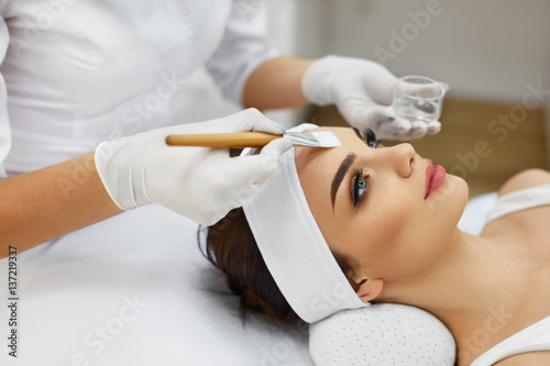 Fototapeta Naklejka Na Ścianę i Meble -  Cosmetician In Spa Salon Hydrating Beautiful Woman's Face