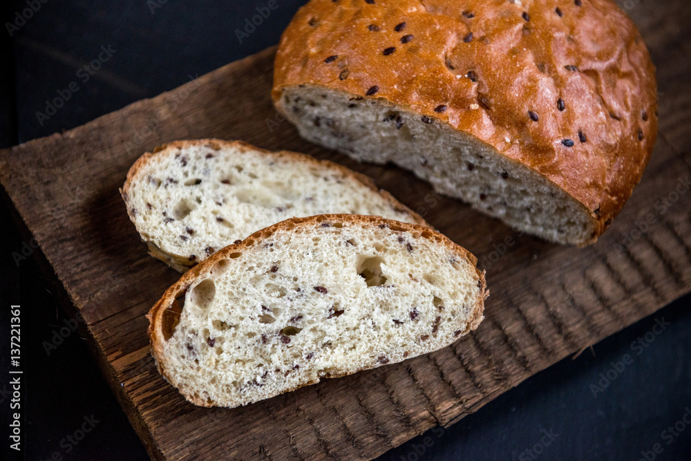 The whole grain bread with flax seeds, on slate and wooden background. The whole grain bread with flax seeds, on slate and wooden background.