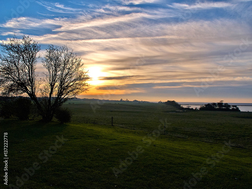 Landscape of green fields and a dramatic sunset