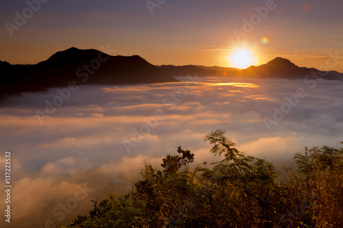 Sun rises from mountain with beautiful golden light on the mist.