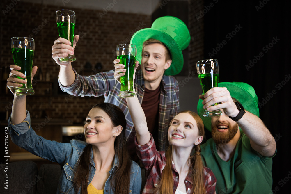cheerful friends holding glasses with beer on St. Patrick's day celebration