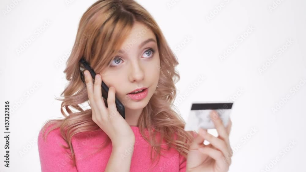 Shocked Woman in pink sweater which talking on the phone and dictates your credit card number Shocked Woman in pink sweater which talking on the phone and dictates your credit card number