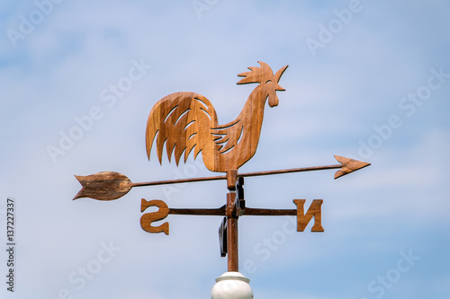 Wooden rooster weathervane showing a wind direction. Traditional weathercock on heaven background. Decorative cock weathervane close up. photo