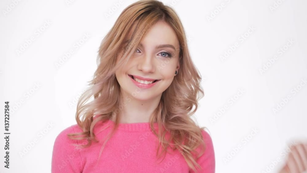 Smiling Woman in pink sweater showing thumb up with open mouth and looking at camera Smiling Woman in pink sweater showing thumb up with open mouth and looking at camera