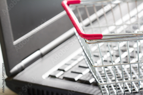 Shopping basket on laptop buying online abstract background concept 