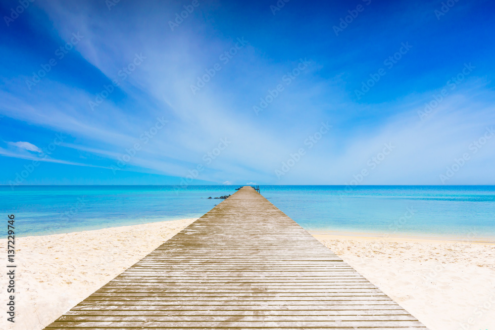Long wooden bridge in Beautiful beaches, crystal clear sea and blue sky with a cloudy.
