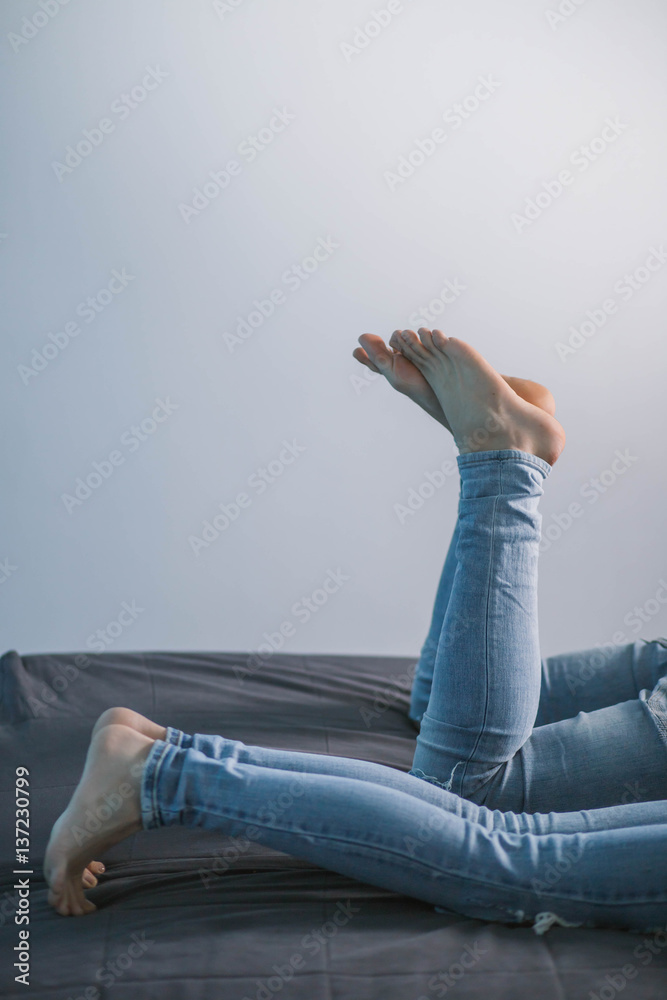 the feet of the boy and girl in jeans lying on the couch barefoot on a blue  background Stock Photo | Adobe Stock