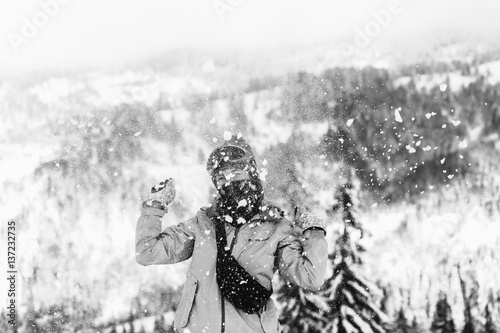 Woman in ski suit throws snow up posing on hill in the mountains