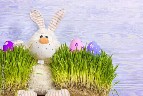 Toy little Easter bunny and Easter eggs on green grass. Easter concept. photo