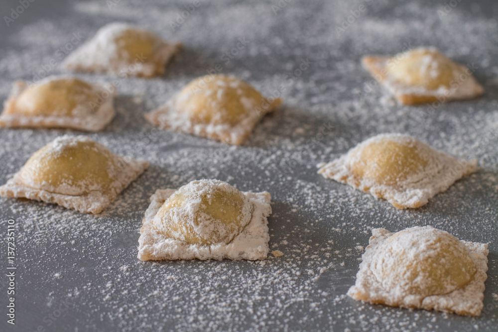 Uncooked homemade ravioli with spinach and ricotta cheese on gray kitchen table. Uncooked homemade ravioli with spinach and ricotta cheese on gray kitchen table.