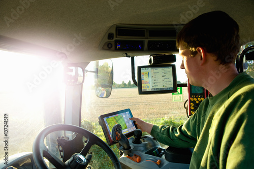 Young man driving tractor using touchscreen on global positioning system photo