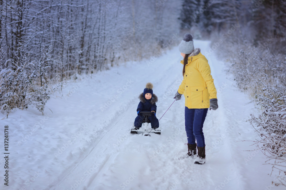 Little boy with mother outdoor. Winter. Sled..