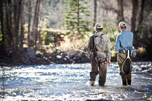 Fishermen ankle deep in river fly fishing, Colorado, USA