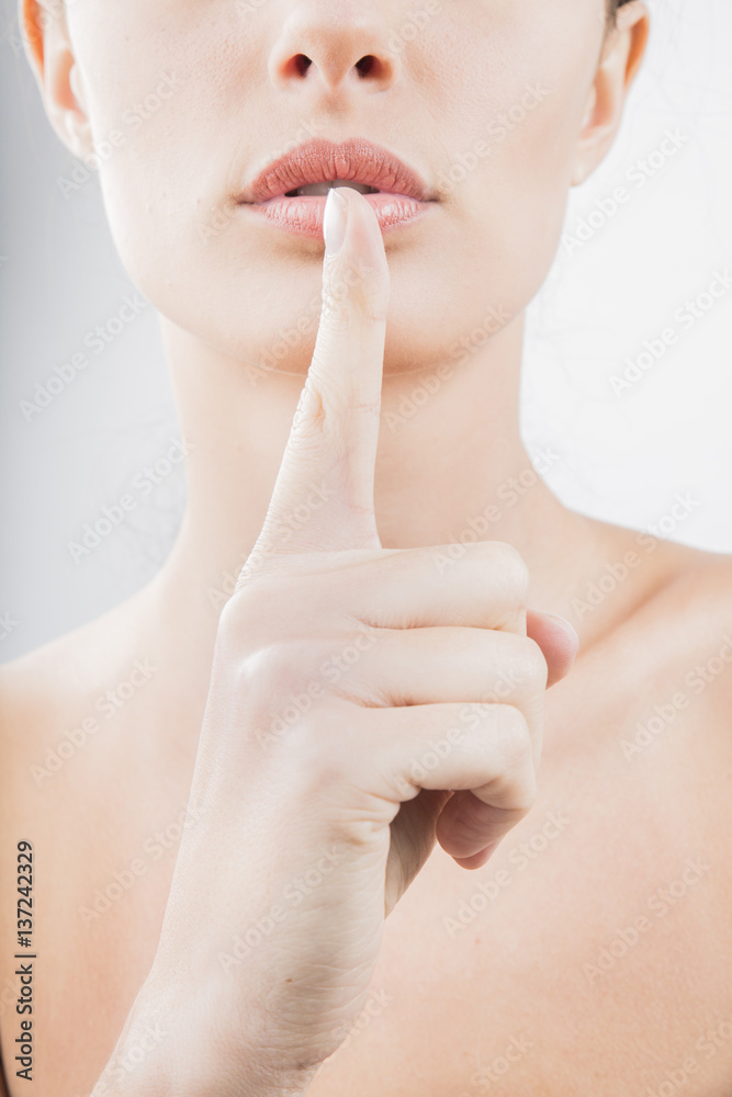the girl put a finger to her lips as sign of silence and secrecy closeup the girl put a finger to her lips as sign of silence and secrecy closeup