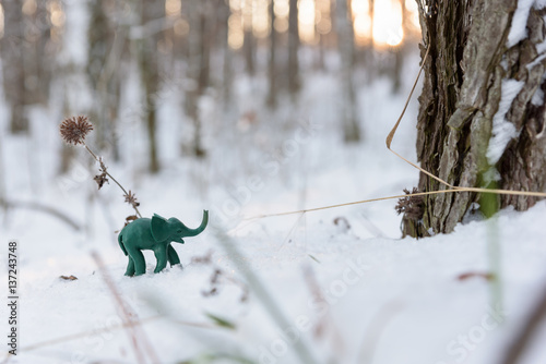 Plasticine green elephant near tree trunk photo