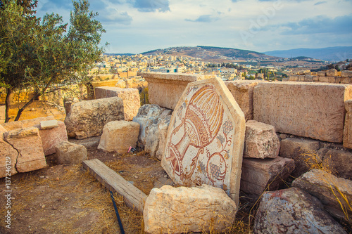 An old Roman mosaic with wine jar and grape in city of Jerash, Jordan