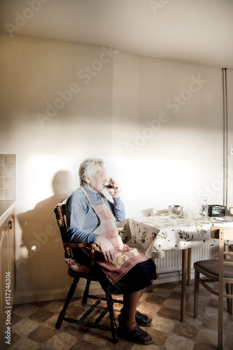 Woman sitting at dining table drinking sherry photo