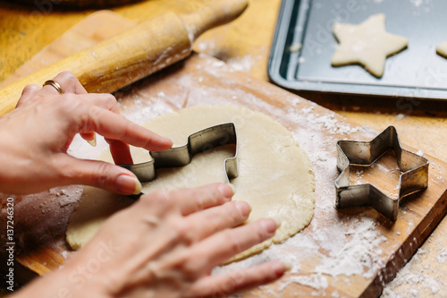 Mature woman pressing cookie cutter into dough, close-up photo