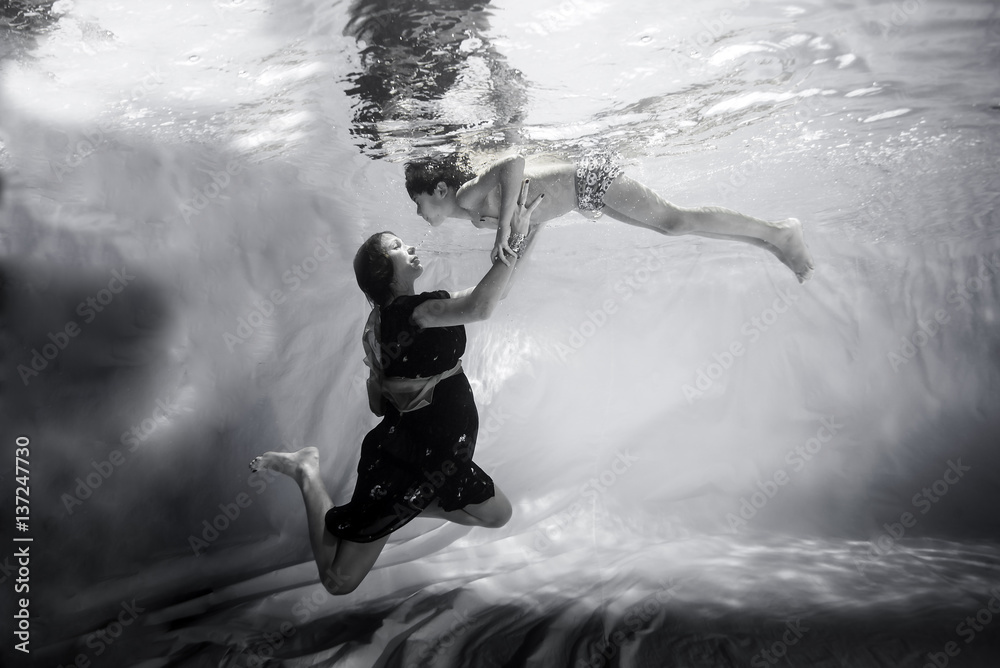 Obraz premium mother takes the hands of her son underwater