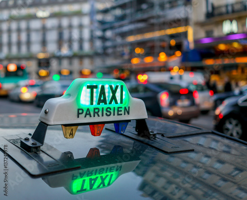 illuminated taxi Parsien sign over blurred Paris boulevard.