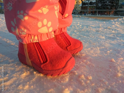 Childhood footwear on the snow at winter street.