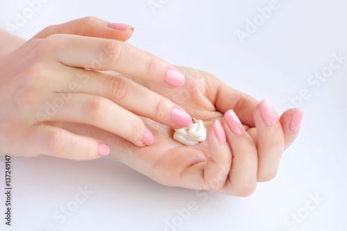Young woman with pink manicure applies cream on her hands