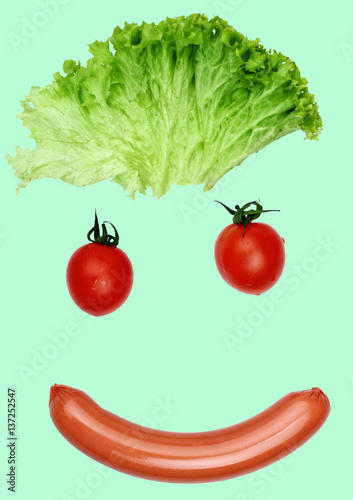 Happy smiling face from food- sausages, lashes salad, pupil mini pumkin.Concept funny food.Food art.Food emotion.Cyan background photo