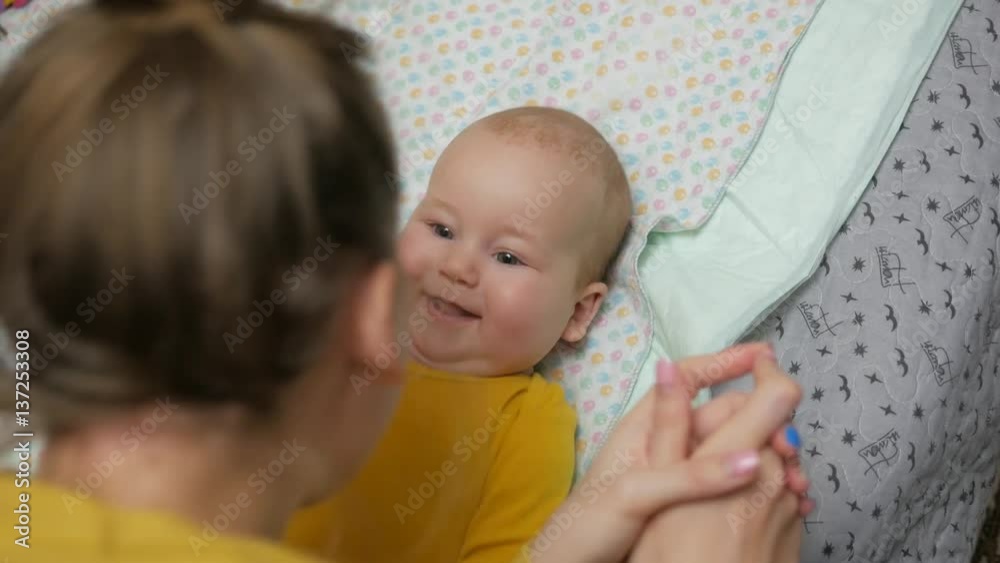 Joyful baby boy laughing while young woman playing with him. Handheld shot