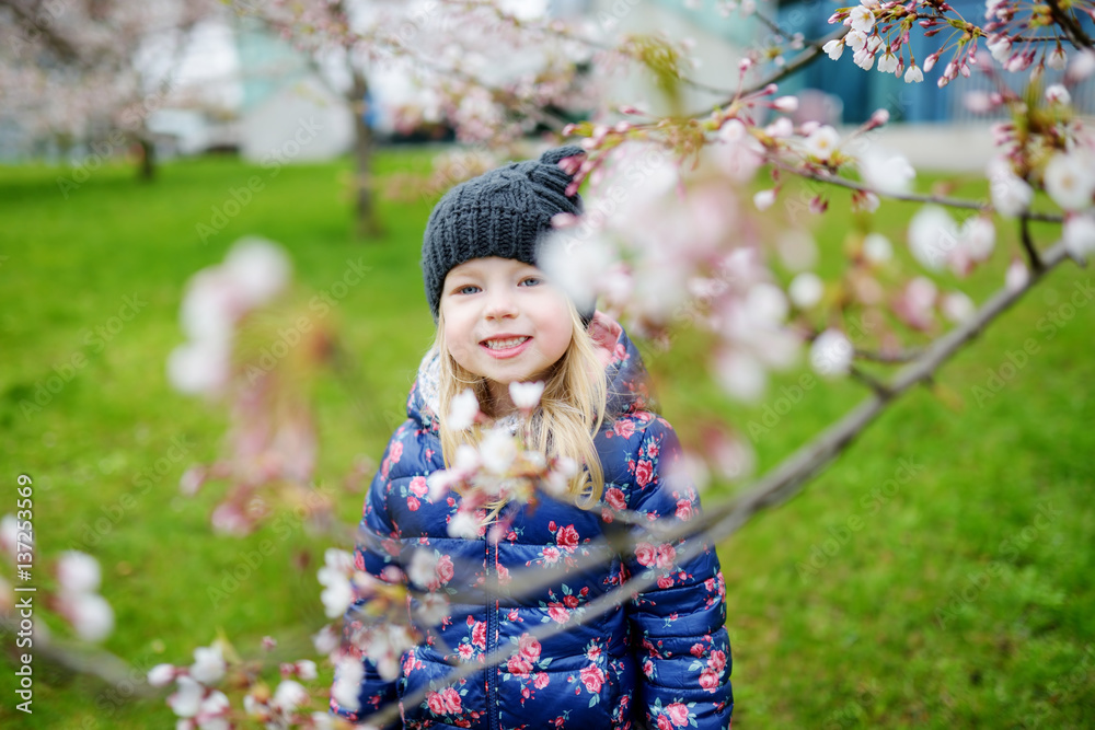 Adorable little girl having fun in blooming cherry garden on beautiful spring day Adorable little girl having fun in blooming cherry garden on beautiful spring day