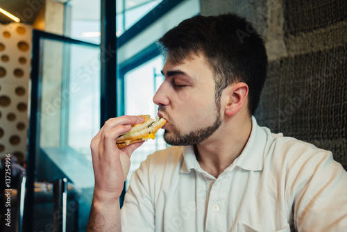 young man enjoys eating fast food in a restaurant