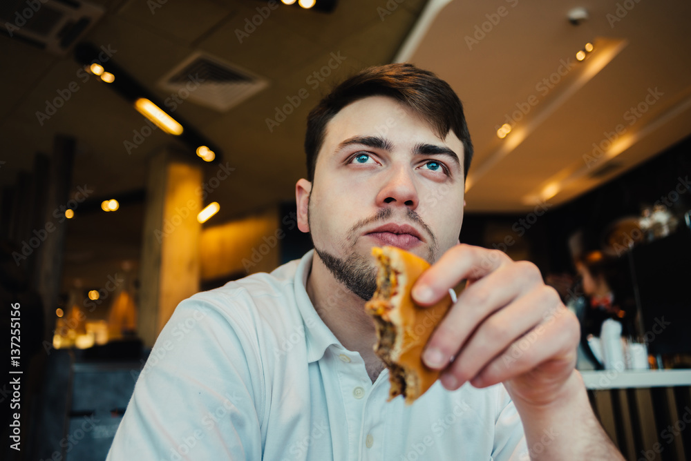 a young man sitting in a nice restaurant fast food burgers and breakfast