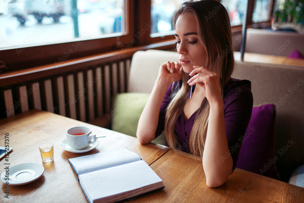 Female writing in notebook in restaurant. Female writing in notebook in restaurant.