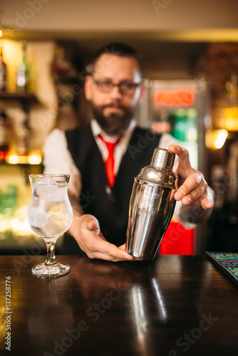 Barman with shaker behind a bar counter