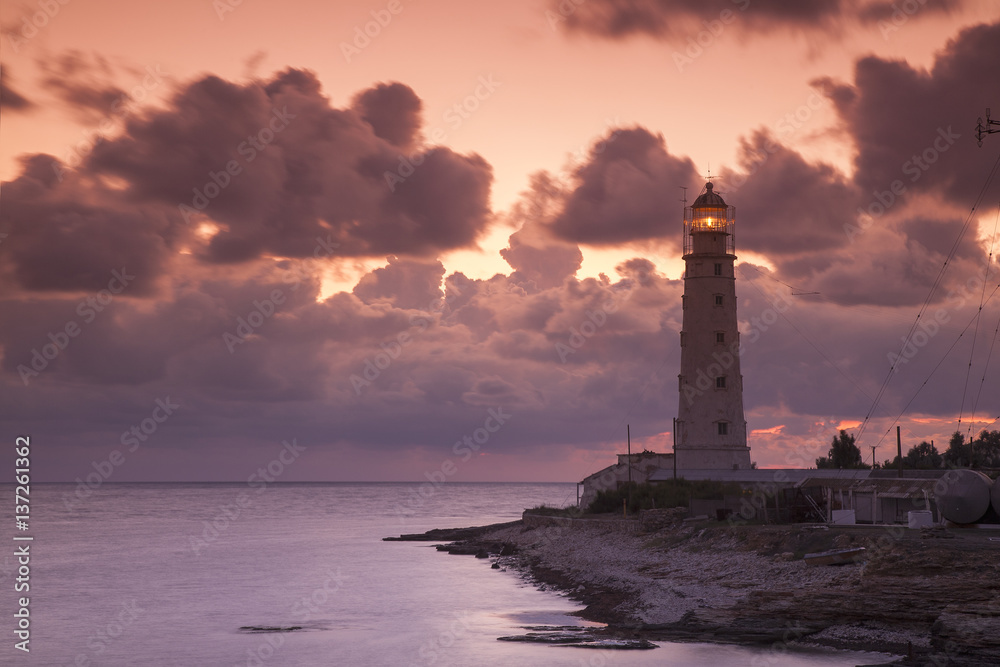pink sunset with clouds behind the old lighthouse
